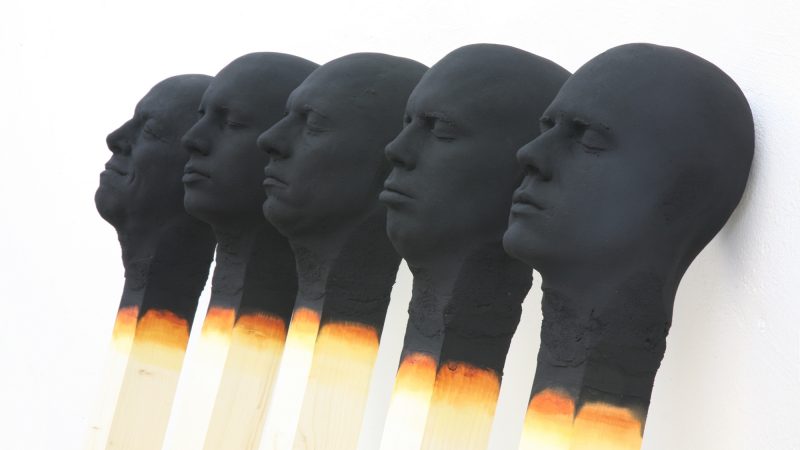 Onopvallende menselijke hoofden lijken in grootschalige lucifers te zijn gebrand door Wolfgang Stiller