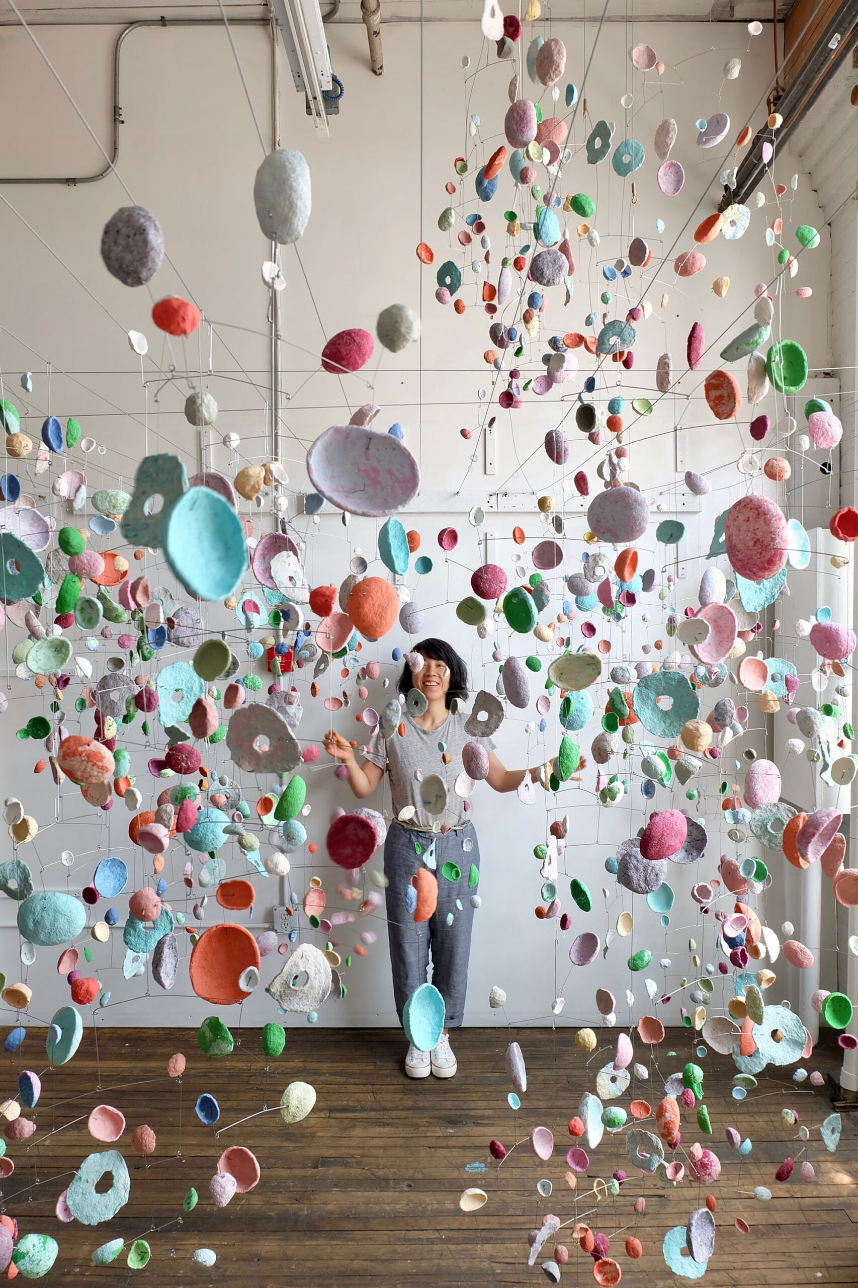 Uitgestrekte mobieltjes van papierpulp van Yuko Nishikawa Hang grillig gekleurde peulen in de lucht